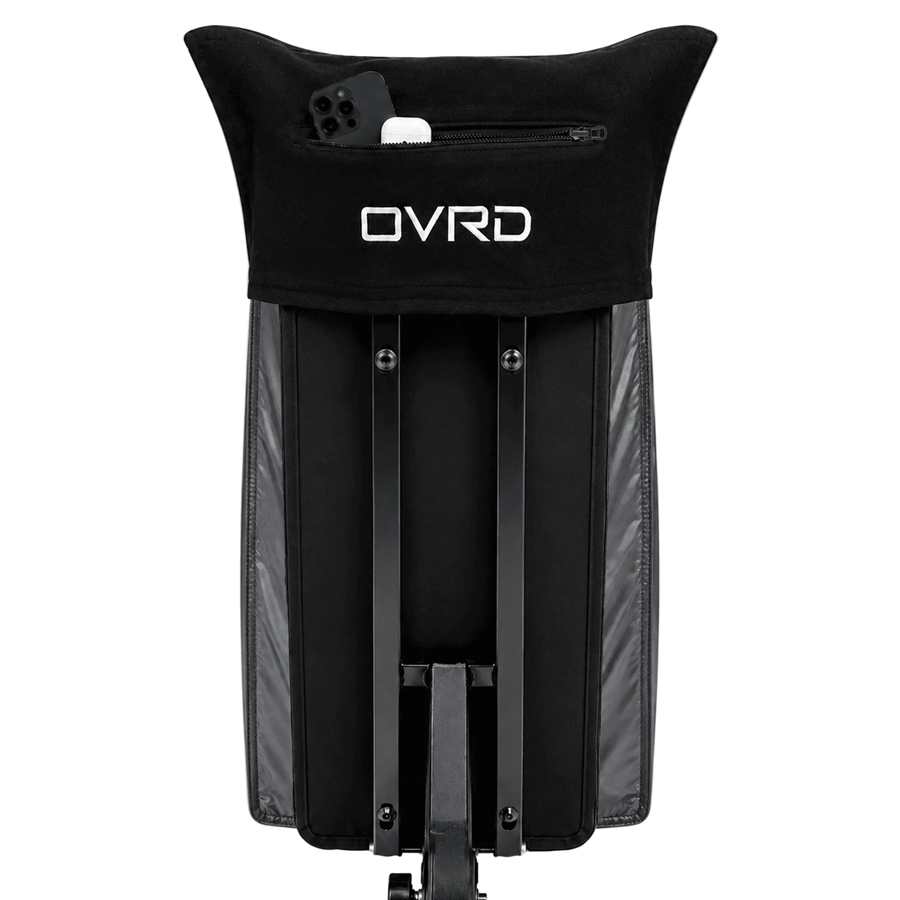 Black OVRD folding stroller seat cover with a zippered pocket on the headrest holding a phone, shown on a white background.